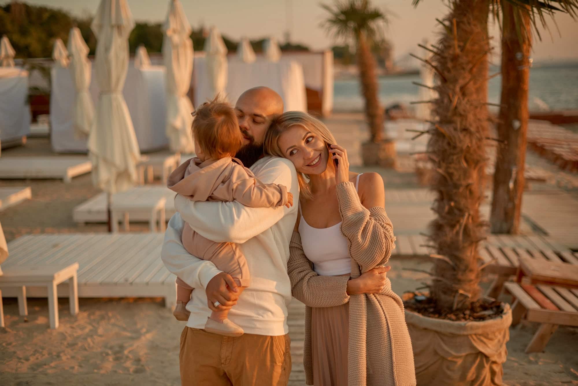 Happy family on beach on vacation in summer holidays. Beautiful woman with man and little girl