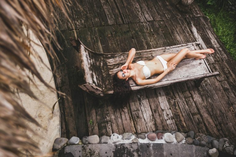 woman-with-long-black-hair-relaxing-on-wooden-chaise-lounge-in-luxury-spa-hotel-bali